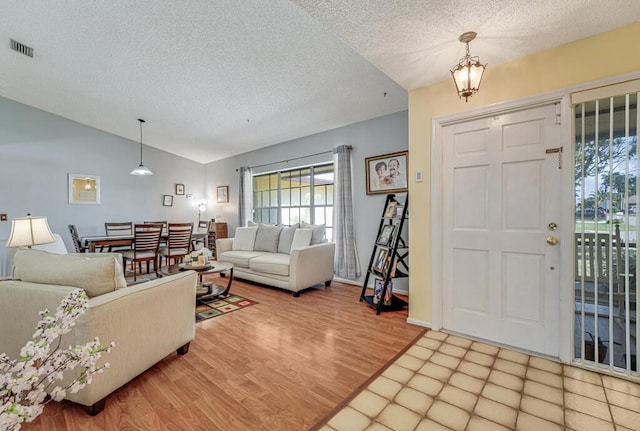 foyer with lofted ceiling, hardwood / wood-style floors, and a textured ceiling