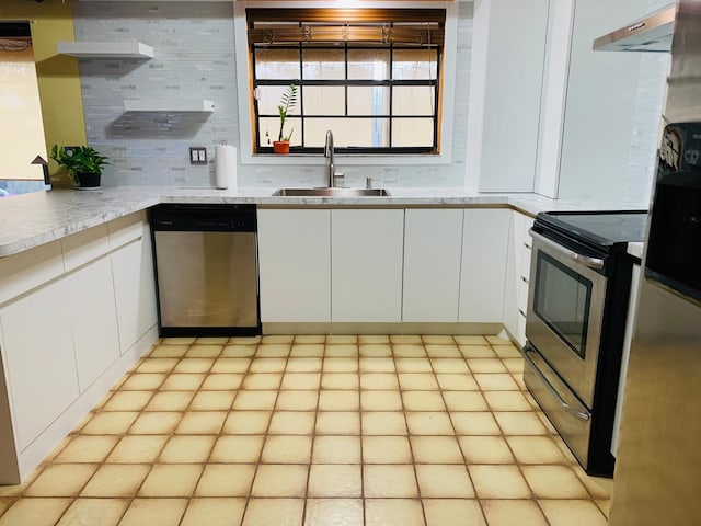 kitchen featuring white cabinets, range hood, appliances with stainless steel finishes, and sink