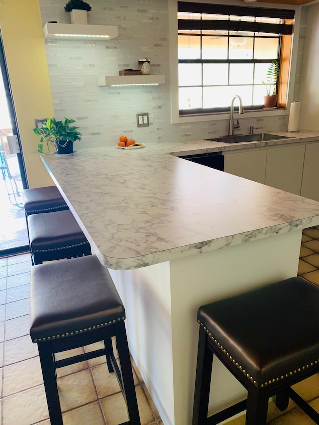 kitchen featuring sink, backsplash, kitchen peninsula, and a breakfast bar area