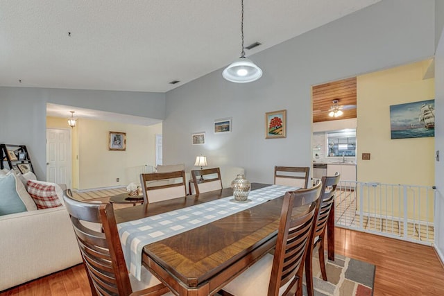 dining area featuring lofted ceiling, sink, and light wood-type flooring