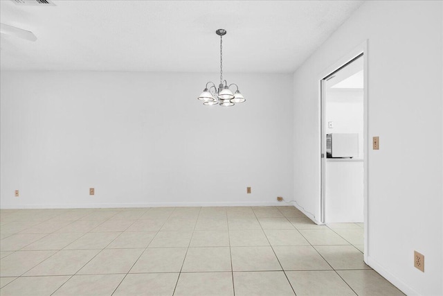 tiled empty room with an inviting chandelier