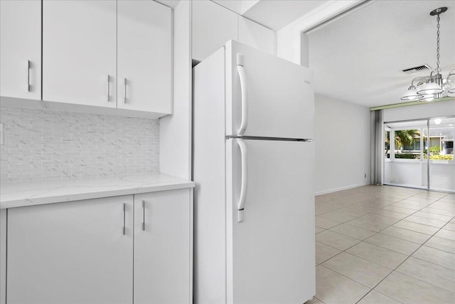 kitchen with backsplash, white cabinets, hanging light fixtures, and white fridge