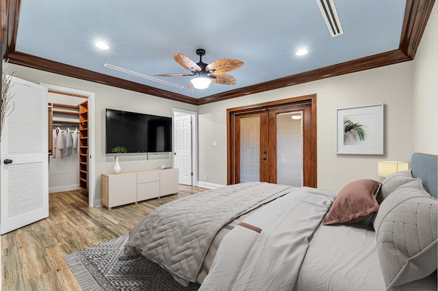 bedroom featuring ornamental molding, a spacious closet, ceiling fan, light hardwood / wood-style floors, and a closet