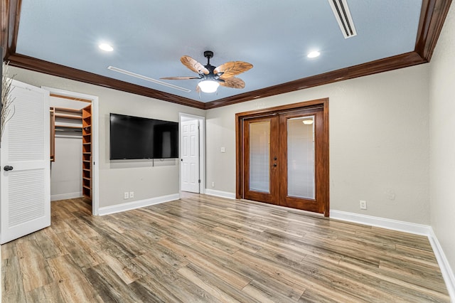 unfurnished bedroom with hardwood / wood-style flooring, ceiling fan, ornamental molding, a spacious closet, and a closet