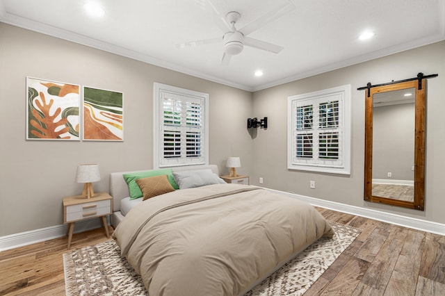 bedroom featuring hardwood / wood-style floors, crown molding, a barn door, and ceiling fan