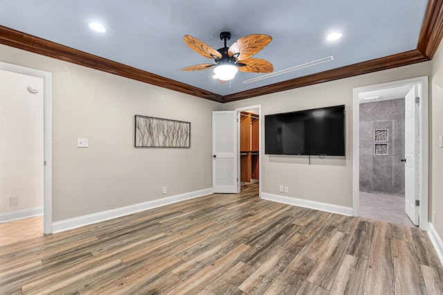 unfurnished bedroom featuring connected bathroom, a spacious closet, ornamental molding, and ceiling fan