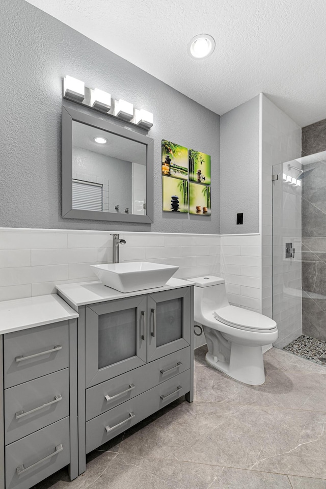 bathroom featuring tiled shower, vanity, toilet, and tile walls