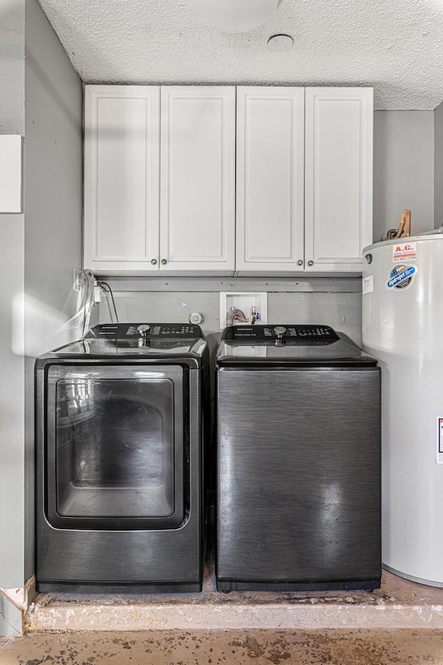 laundry room featuring cabinets, washing machine and dryer, water heater, and a textured ceiling