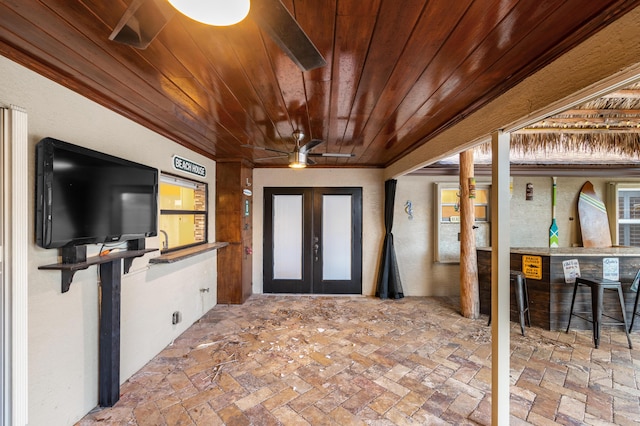 interior space with french doors, ceiling fan, and exterior bar