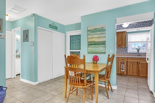 dining space featuring sink, electric panel, and light tile patterned floors