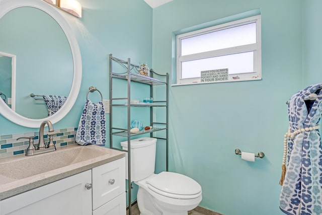 bathroom with vanity, toilet, and decorative backsplash