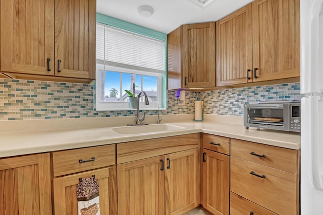 kitchen featuring sink, white refrigerator, and tasteful backsplash