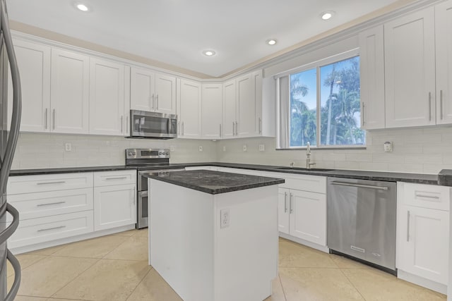 kitchen featuring white cabinets, appliances with stainless steel finishes, a center island, sink, and light tile patterned floors