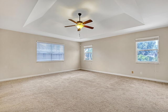 unfurnished room featuring ceiling fan, a tray ceiling, and carpet flooring