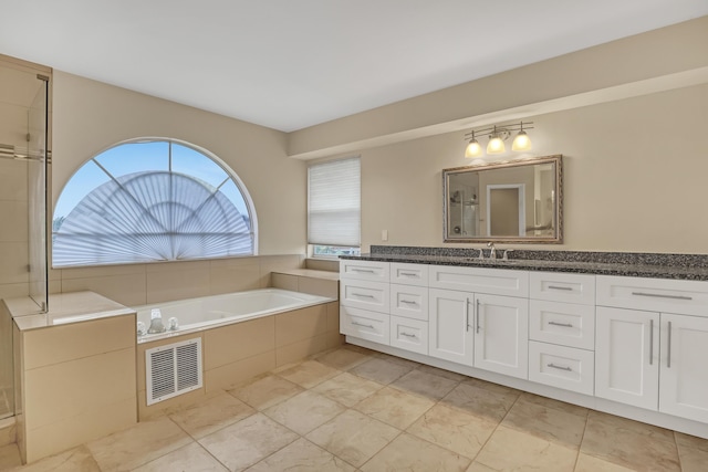 bathroom featuring tiled tub and vanity