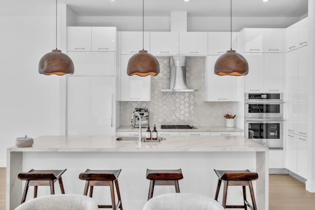 kitchen with white cabinetry, wall chimney range hood, tasteful backsplash, sink, and black gas cooktop