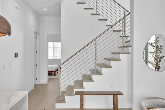 staircase featuring a towering ceiling and hardwood / wood-style flooring