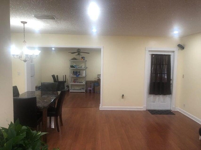 dining space with a textured ceiling, dark hardwood / wood-style flooring, and an inviting chandelier