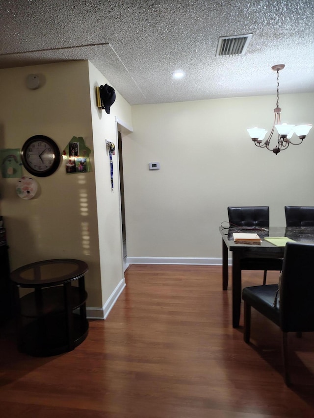 dining area with hardwood / wood-style floors, a textured ceiling, and a chandelier