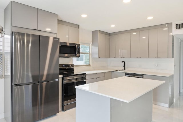 kitchen featuring a sink, light countertops, appliances with stainless steel finishes, gray cabinets, and a center island