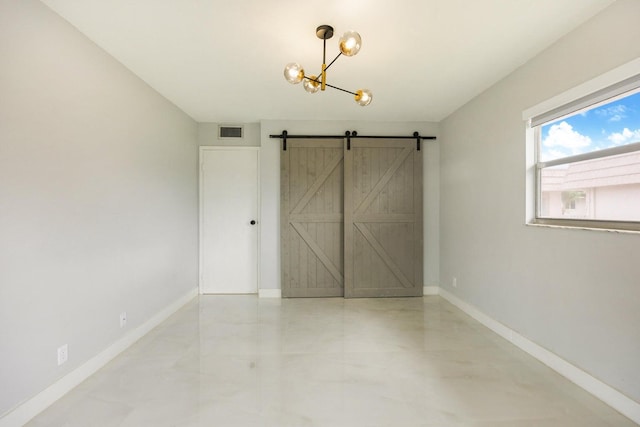 unfurnished room with an inviting chandelier, a barn door, visible vents, and baseboards