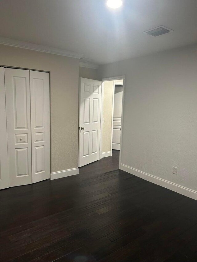 empty room featuring crown molding and dark hardwood / wood-style floors