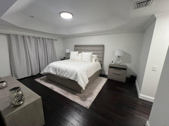 bedroom with ornamental molding, dark hardwood / wood-style floors, and a raised ceiling