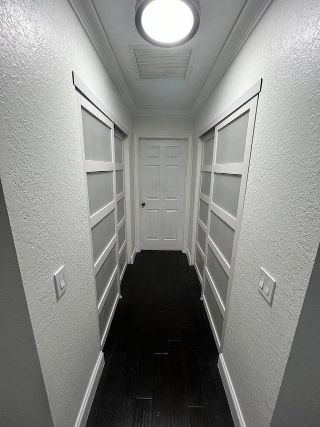 hall featuring crown molding, built in shelves, and dark hardwood / wood-style flooring