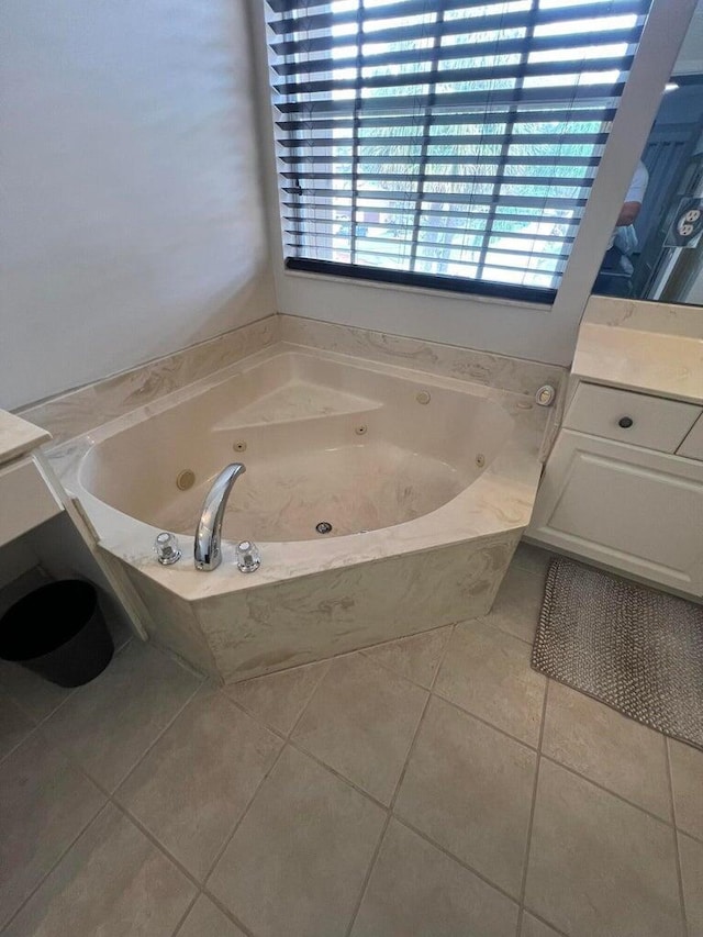 bathroom featuring tiled tub, vanity, and tile patterned flooring