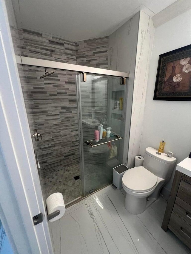 bathroom with toilet, a shower with shower door, and vanity