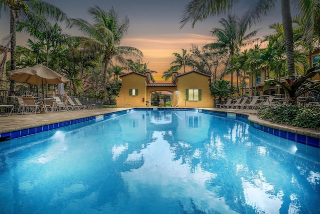 pool at dusk featuring a patio