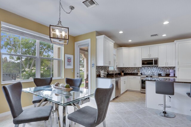 kitchen with visible vents, white cabinets, dark countertops, decorative light fixtures, and stainless steel appliances