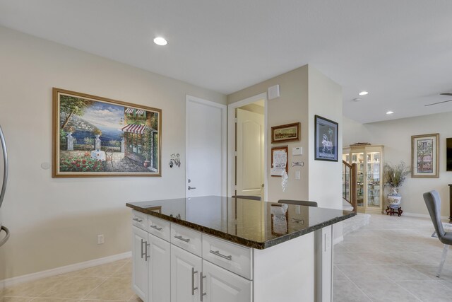 kitchen featuring a center island, recessed lighting, white cabinets, light tile patterned flooring, and dark stone countertops