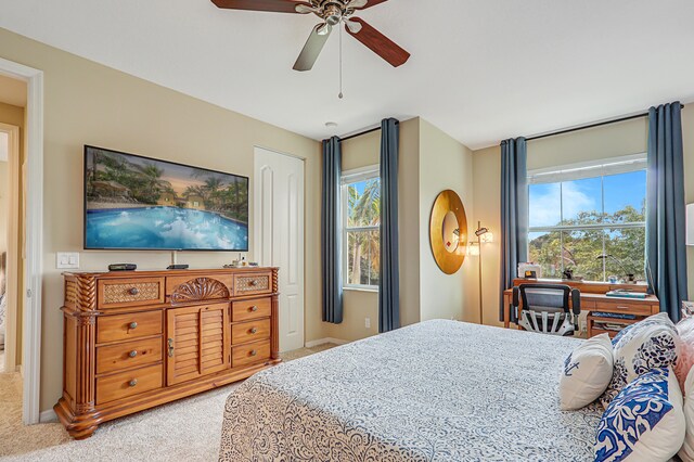 bedroom featuring baseboards, multiple windows, a ceiling fan, and light colored carpet