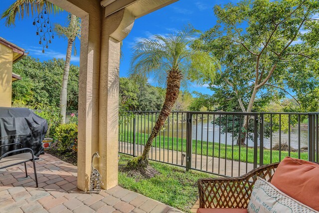 view of patio featuring fence private yard, a water view, and a grill