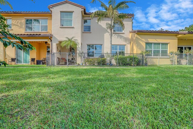 back of property with a lawn, fence, and stucco siding