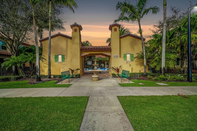 view of front of house featuring a tiled roof, a front lawn, and stucco siding