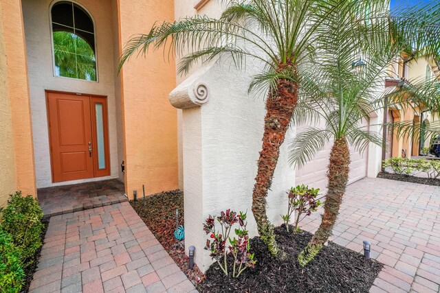 entrance to property featuring a garage and stucco siding