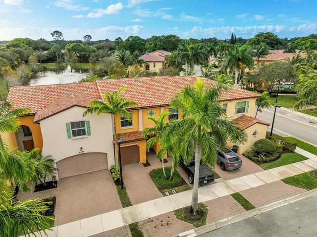 mediterranean / spanish house featuring an attached garage, a tile roof, and stucco siding