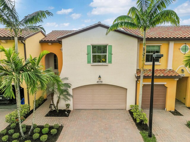 mediterranean / spanish-style home featuring decorative driveway, a tile roof, and stucco siding