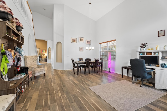 office area with dark hardwood / wood-style floors, a towering ceiling, and a notable chandelier