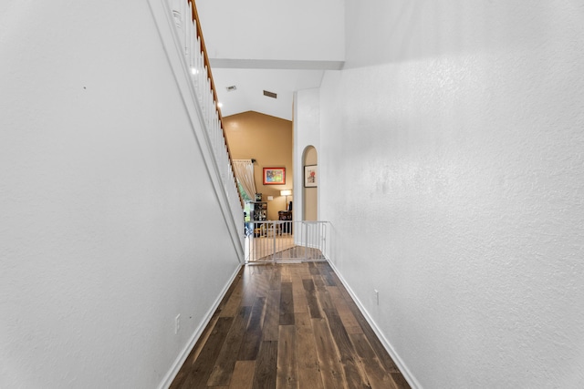 hallway featuring high vaulted ceiling and dark wood-type flooring