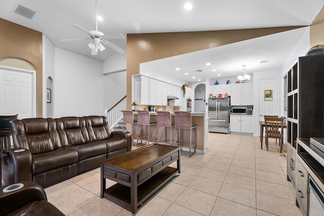 tiled living room with ceiling fan with notable chandelier and lofted ceiling