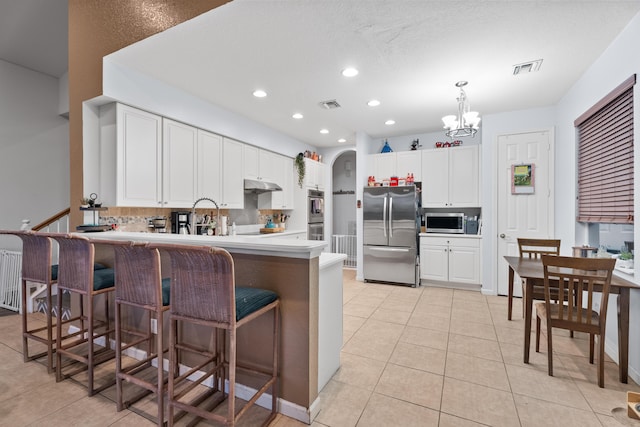 kitchen with a kitchen breakfast bar, white cabinets, light tile patterned floors, and appliances with stainless steel finishes