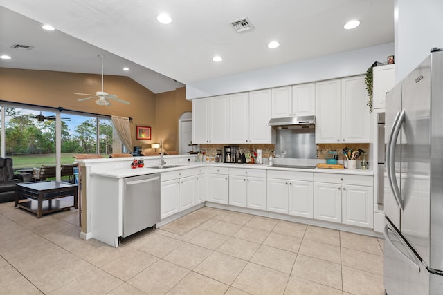 kitchen featuring appliances with stainless steel finishes, decorative backsplash, sink, kitchen peninsula, and lofted ceiling