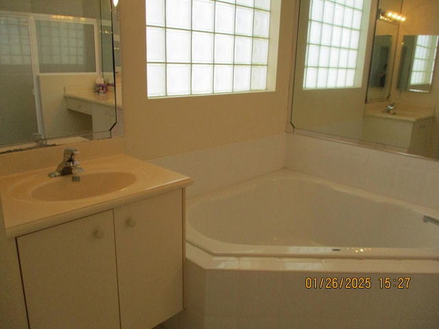 bathroom featuring tiled tub and vanity