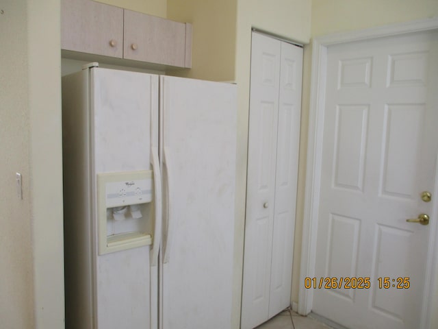 interior space with light tile patterned floors, light brown cabinets, and white fridge with ice dispenser