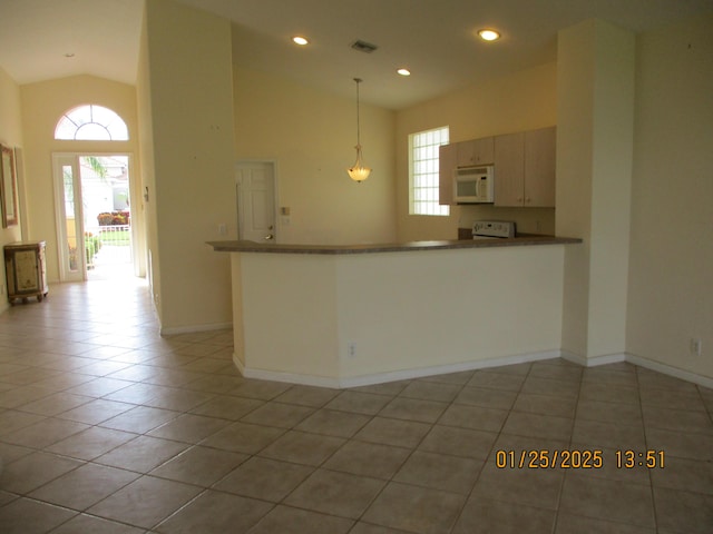 kitchen featuring light tile patterned flooring, high vaulted ceiling, decorative light fixtures, stove, and kitchen peninsula