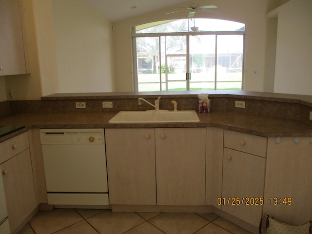 kitchen featuring lofted ceiling, sink, light tile patterned floors, and white dishwasher