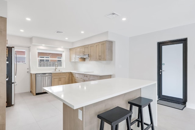 kitchen featuring sink, stainless steel appliances, a breakfast bar, and light brown cabinets